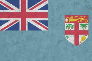 Fiji flag depicted in bright paint colors on old relief plastering wall. Textured banner on rough background photo