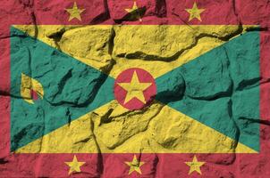 Grenada flag depicted in paint colors on old stone wall closeup. Textured banner on rock wall background photo