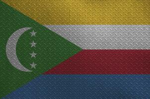 Comoros flag depicted in paint colors on old brushed metal plate or wall closeup. Textured banner on rough background photo