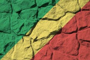 Congo flag depicted in paint colors on old stone wall closeup. Textured banner on rock wall background photo