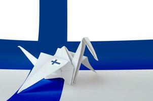 Finland flag depicted on paper origami crane wing. Handmade arts concept photo