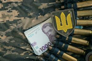 Ukrainian army machine gun belt shells and bunch of hryvnia bills on military uniform. Payments to soldiers of the Ukrainian army, salaries to the military photo