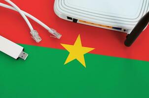 Burkina Faso flag depicted on table with internet rj45 cable, wireless usb wifi adapter and router. Internet connection concept photo
