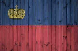 Liechtenstein bandera representado en brillante pintar colores en antiguo de madera pared. texturizado bandera en áspero antecedentes foto