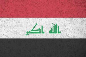 Iraq flag depicted in bright paint colors on old relief plastering wall. Textured banner on rough background photo