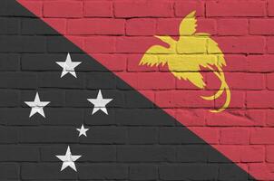 Papuasia nuevo Guinea bandera representado en pintar colores en antiguo ladrillo pared. texturizado bandera en grande ladrillo pared albañilería antecedentes foto