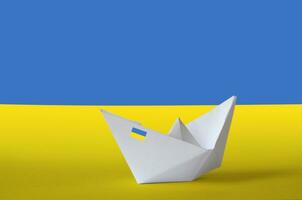 Ukraine flag depicted on paper origami ship closeup. Handmade arts concept photo