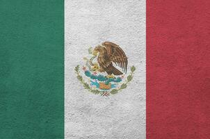 Mexico flag depicted in bright paint colors on old relief plastering wall. Textured banner on rough background photo