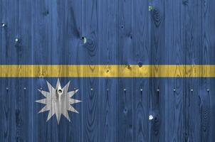 Nauru flag depicted in bright paint colors on old wooden wall. Textured banner on rough background photo