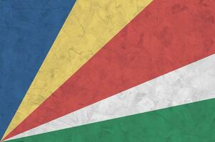 Seychelles flag depicted in bright paint colors on old relief plastering wall. Textured banner on rough background photo