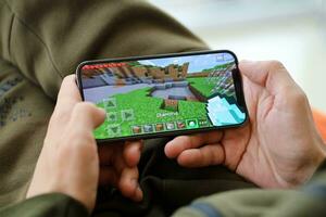 Minecraft mobile iOS game on iPhone 15 smartphone screen in male hands during mobile gameplay photo