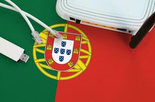 Portugal flag depicted on table with internet rj45 cable, wireless usb wifi adapter and router. Internet connection concept photo