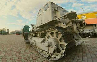 Photo of a gray bulldozer among the railway trains. Strong distortion from the fisheye lens