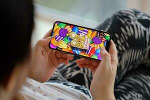 Candy Crush Saga mobile iOS game on iPhone 15 smartphone screen in female hands during mobile gameplay photo