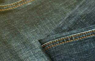 Detailed abstract texture of dark blue denim cloth. Background image of old used denim trousers fabric photo