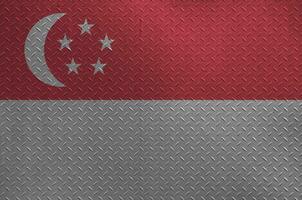 Singapore flag depicted in paint colors on old brushed metal plate or wall closeup. Textured banner on rough background photo
