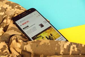 KYIV, UKRAINE - 4 MAY, 2023 Focus ukrainian news portal on smartphone screen with ukrainian flag and camouflage fabric photo