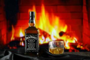 KYIV, UKRAINE - MAY 4, 2022 Jack Daniels original alcohol bottle on wooden table with red fireplace photo