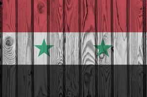 Syria flag depicted in bright paint colors on old wooden wall. Textured banner on rough background photo