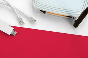 Poland flag depicted on table with internet rj45 cable, wireless usb wifi adapter and router. Internet connection concept photo