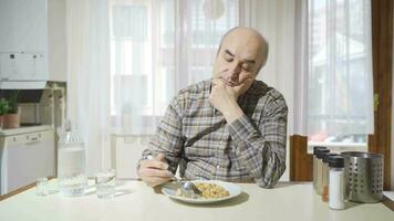 Unhappy thoughtful old man does not eat in the kitchen. video