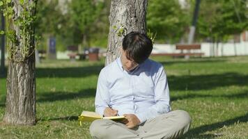 Young man writing diary outdoors. video