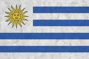 Uruguay flag depicted in bright paint colors on old relief plastering wall. Textured banner on rough background photo