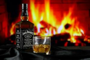 KYIV, UKRAINE - MAY 4, 2022 Jack Daniels original alcohol bottle on wooden table with red fireplace photo