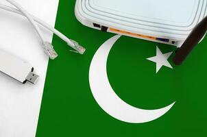 Pakistan flag depicted on table with internet rj45 cable, wireless usb wifi adapter and router. Internet connection concept photo