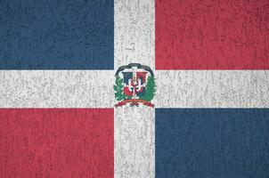 Dominican Republic flag depicted in bright paint colors on old relief plastering wall. Textured banner on rough background photo