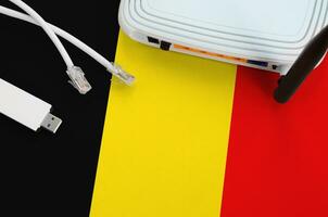 Belgium flag depicted on table with internet rj45 cable, wireless usb wifi adapter and router. Internet connection concept photo