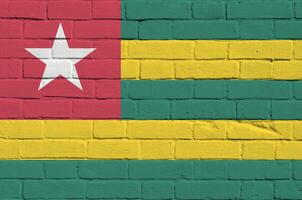 Togo flag depicted in paint colors on old brick wall. Textured banner on big brick wall masonry background photo