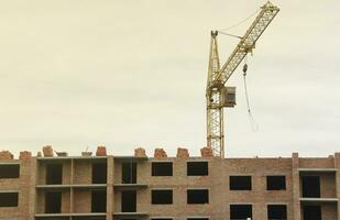 View of a large construction site with buildings under construction and multi-storey residential homes. Tower cranes in action on blue sky background. Housing renovation concept photo