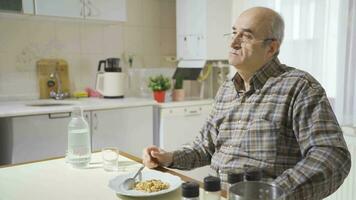 pensativo antiguo hombre come en el cocina. video