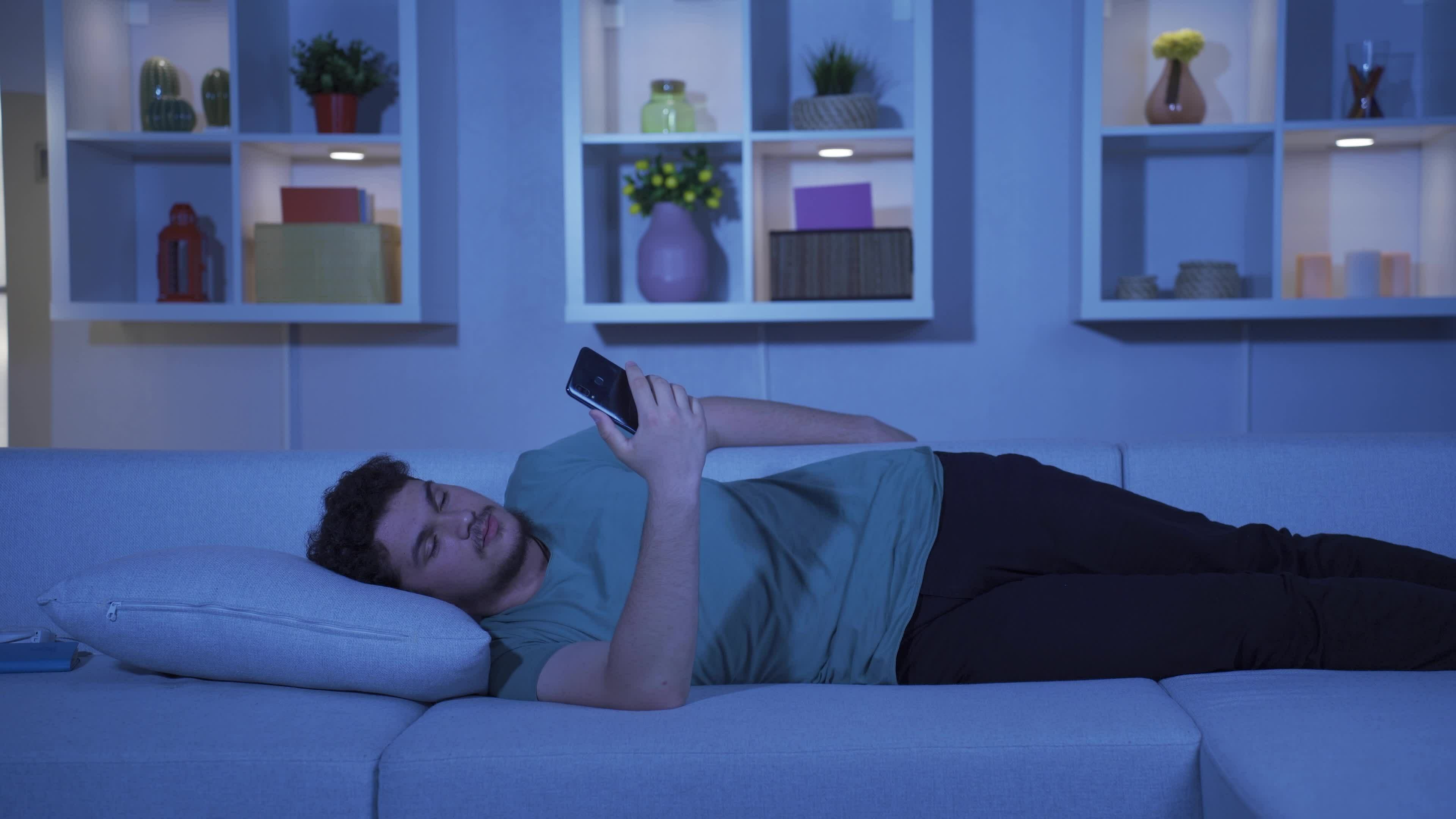 Man falling asleep at night with phone in hand. Phone addiction