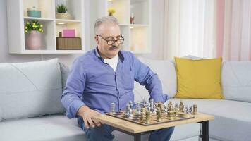 The old man is playing chess at home alone and bored. video