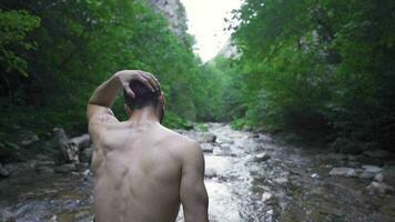 sur le courant dans le forêt Adam se redresse le sien humide cheveux. video