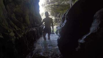 jovem homem entrando a mar caverna. video