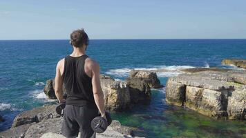 sportlich jung Mann Heben Gewichte beim das Strand. video