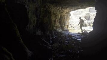 Young man walking in sea cave. video
