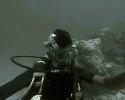 un hombre debajo el Oceano es visto desgastado el oxígeno máscara y el buceo accesorios foto