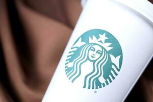 KHARKOV, UKRAINE - MARCH 15, 2021 Starbucks cup with green logo. Starbucks Corporation is multinational chain of coffeehouses headquartered in Seattle, Washington photo