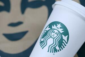 KHARKOV, UKRAINE - MARCH 15, 2021 Starbucks cup with green logo. Starbucks Corporation is multinational chain of coffeehouses headquartered in Seattle, Washington photo