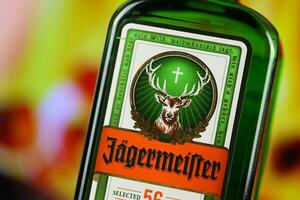 KYIV, UKRAINE - MAY 4, 2022 Jagermeister original alcohol bottle on wooden table with red fireplace photo