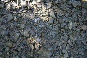 antecedentes de destrozado pedregoso piedras superficie en montaña área. textura con natural ligero foto