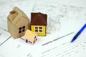 Residential construction agreement ready to sign with small toy houses and pen. Construction contract photo