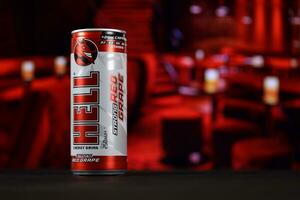 KHARKOV, UKRAINE - FEBRUARY 14, 2021 Hell energy drink can on black wooden table with red interior background photo