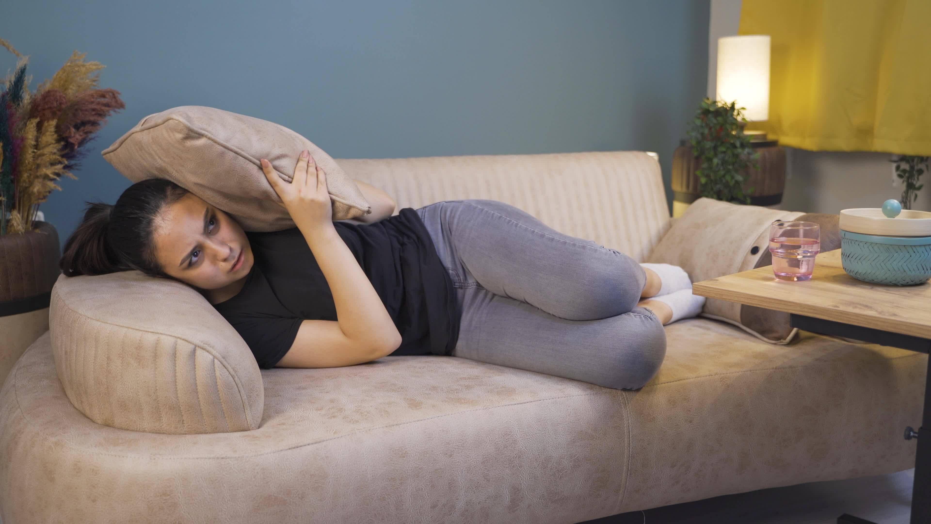 The woman who presses the pillows on her head with fear. 33548312 Stock