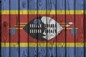 Swaziland flag depicted in bright paint colors on old wooden wall. Textured banner on rough background photo