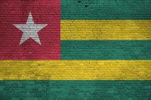 Togo flag depicted in paint colors on old brick wall. Textured banner on big brick wall masonry background photo